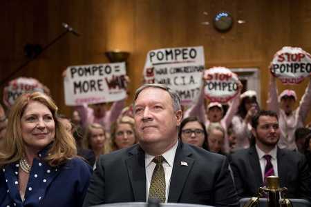 Protesters wave placards as Secretary of State-nominee Mike Pompeo, the outgoing CIA director, begins testimony April 12 during his confirmation hearing before the Senate Foreign Relations Committee. (Photo: JIM WATSON/AFP/Getty Images)
