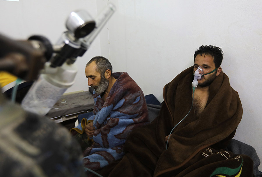 Syrians reportedly suffering from breathing difficulties following Syrian regime’s Feb. 4 air strikes on the northwestern town of Saraqeb rest around a stove at a field hospital. (Photo: Omar Haj Kadour/AFP/Getty Images)