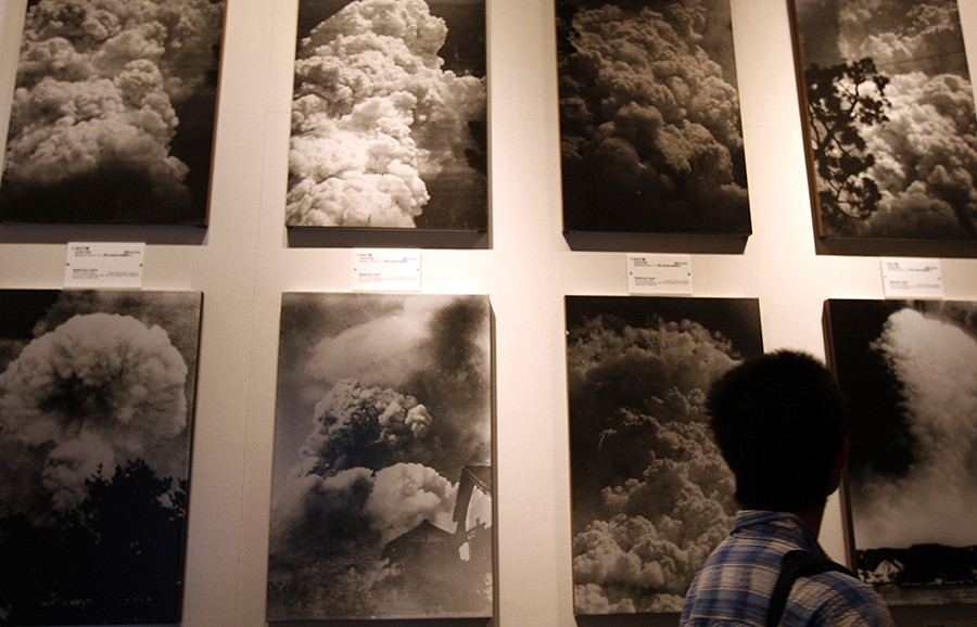 A visitor to the Peace Memorial Museum in Hiroshima walks by images of the mushroom cloud that erupted when the atomic bomb was dropped in 1945. An estimated 70,000 people were killed instantly and afterward, many thousands more died from radiation. Nearly four decades later, nuclear weapons remain a serious threat. (Photo by Junko Kimura/Getty Images)
