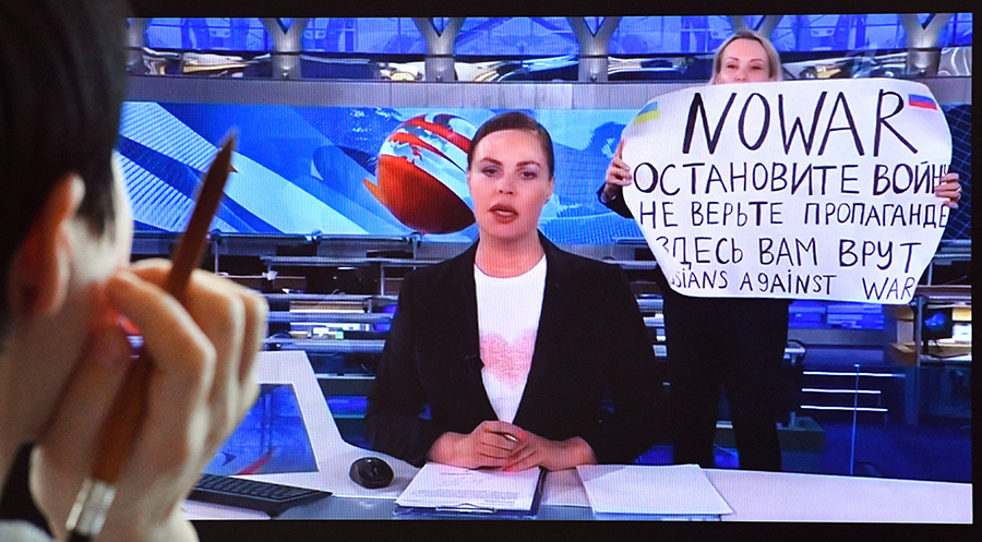 A woman looks at a computer screen showing a dissenting Russian Channel One employee, Marina Ovsyannikova, entering an on-air TV studio during Russia's most-watched evening news broadcast on March 15. The protester held a poster reading 