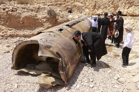 Ultra-Orthodox Jews gather on April 30 around the remains of one of the ballistic missiles, fired by Iran earlier in the month and intercepted by Israel, that landed in an open area of the Negev desert. (Photo by Menahem Kahana/AFP via Getty Images)