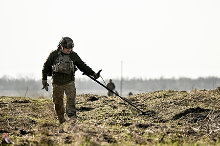 A Ukrainian soldier scans the ground with a metal detector while clearing the deoccupied territory of Ukraine’s Kerson region in November. (Photo by Dmytro Smolienko/Ukrinform/NurPhoto via Getty Images)