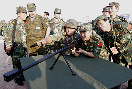 Chinese military officers try out a Russian-made rifle at the conclusion of the two countries' first joint military exercise August 25, 2005 in eastern China's Shandong Province. More than 7,000 Chinese troops and 1,800 Russian troops took part in the exercise which included a mock invasion by paratroopers on China's east coast. (Photo by China Photos/Getty Images)
